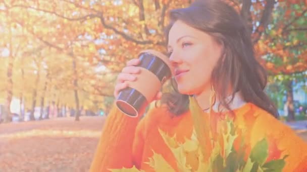 Feliz mulher sorridente com folhas de outono bebendo caffee no parque de outono , — Vídeo de Stock