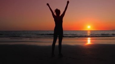 Okyanus kıyısındaki spor elbiseleri giyen kadın, spor başarılarından zevk alıyor..