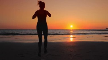 Okyanus kıyısında koşan kadın, spor başarılarının tadını çıkarıyor..