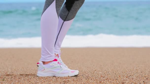 Atletische vrouw op het strand van de oceaan, warm-up voor de oefening — Stockvideo