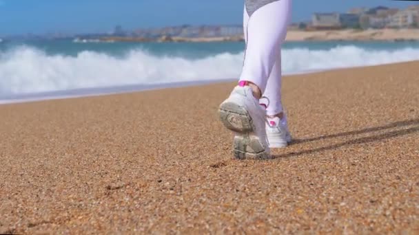 Атлетичні ноги молодої жінки, що йдуть на піщаному пляжі — стокове відео