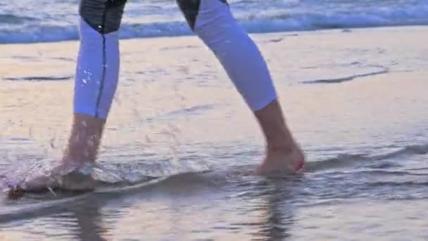 Close-up de gils pés descalços na espuma do mar e água. Pôr do sol — Vídeo de Stock