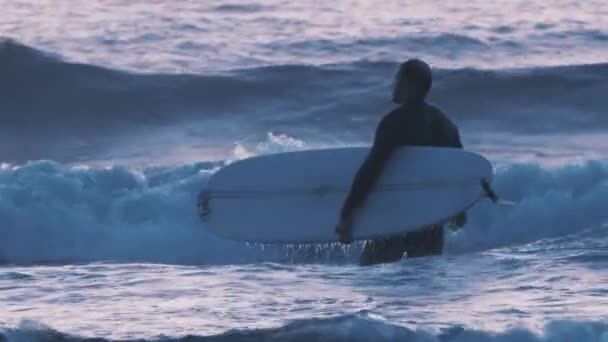 Surfer człowiek z deską surfingową idzie spotkać fale — Wideo stockowe