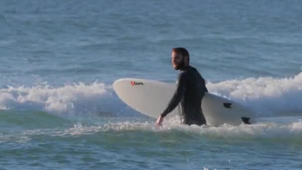 Surfista com sua prancha caminhando em direção ao oceano, ondas do oceano — Vídeo de Stock