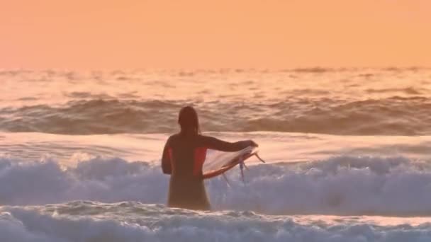 彼のサーフボードを持つサーファーの女性は海の波に会いに行く — ストック動画