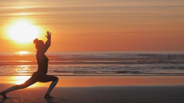 Slim kobieta z ramionami podniesione na plaży o pięknym zachodzie słońca — Wideo stockowe