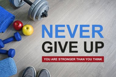 Asla pes etmeyin. Sandığından daha güçlü. Fitness motivasyonel tırnak. Spor tema. Sağlıklı ve aktif yaşam tarzı kavramı. Spor ayakkabı, halter, elma ve bir egzersiz mat gri ahşap zemin üzerine. 