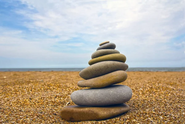 Stones pyramid on sand symbolizing zen, harmony, balance. Sea in the background