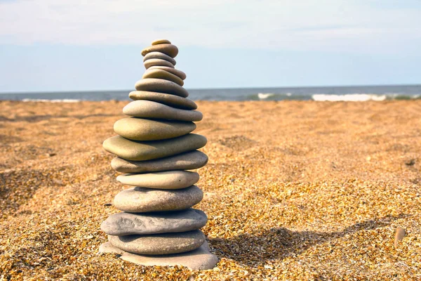 Stones pyramid on sand symbolizing zen, harmony, balance. Sea in the background