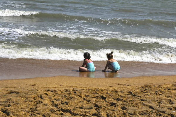 在海滩上玩蓝色泳装的两个小女孩 — 图库照片