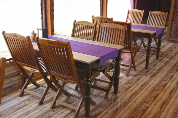 The simple interior of the cafe with wooden furniture and purple decoration.