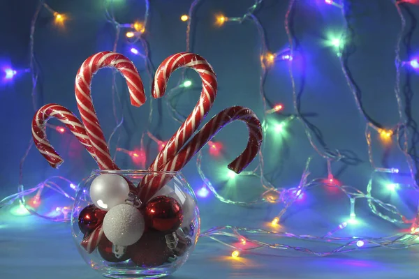 四个圣诞糖果 以心脏的形式 条纹藤条 在彩色花环的背景下 — 图库照片