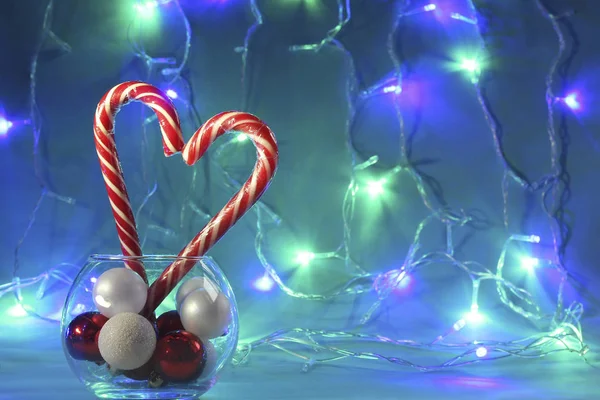 Zwei Weihnachtsbonbons Herzform Gestreifte Stöcke Vor Dem Hintergrund Farbiger Girlanden lizenzfreie Stockbilder