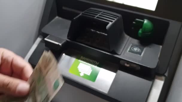 Мужчина держит наличные, размытое изображение девушки вставить карту в банкомат в качестве фона . — стоковое видео