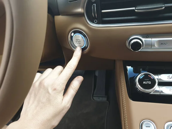 Woman presses the start button to start the car