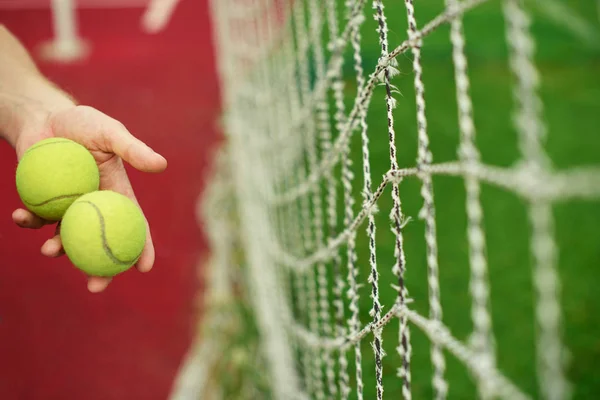 Close up of tennis balls in hands on tennis court.