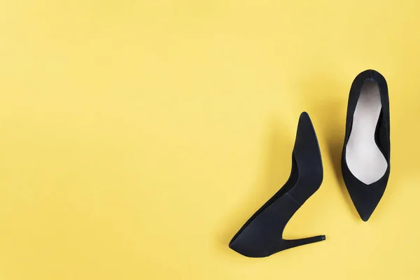 Stylish fashion black shoes high heels on yellow background. Flat lay, top view trendy background. Fashion blog look. Add your text.
