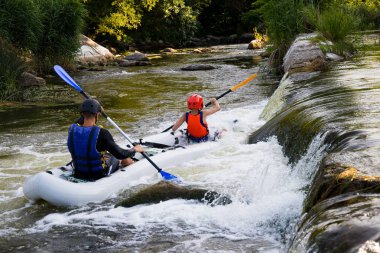 Parlak loitering sporcularda ve Koruyucu baretler bir şişme botla kürek kürek ile iki çocuk akıntıyla birlikte mücadele yarışmalar fırtınalı bir nehirde rafting katılan