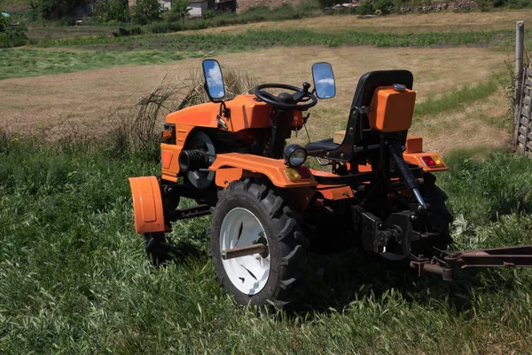 橙色的 Minitractor 在田里工作 农用多功能机带拖车收集收获 — 图库照片