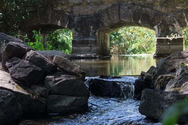 Beautiful ancient stone arch bridge over a river stream with reflection in the water. Ancient bridge in the national park Europe. Creek under the arches of the ancient castle bridge with reflection in the water
