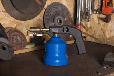 Gaz el ile kaynak makinesi bileme tekerlekleri ve araçları içinde belgili tanımlık geçmiş bulanık bir ev atölye bir tezgah üzerinde duruyor