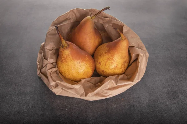 three yellow pears in a paper bag