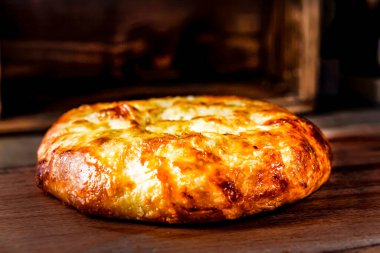 Doğu Türk peynirli keki ahşap bir masanın üzerinde yatıyor. Peynirli Pita bir restorandaki eski ahşap masada yatıyor. Gürcü Khachapuri, kubdari, peynirli lobiani. Peynirli lezzetli ekmek. Ev yapımı pişirme