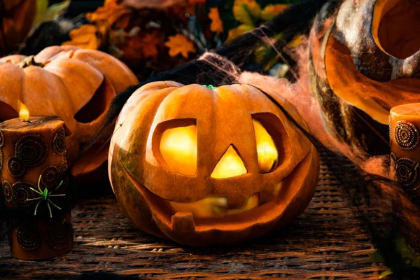 Jack lamp for pumpkin Halloween celebration. Festive composition of pumpkins with carved scary faces with luminous eyes and candles. All Saints\' Day.