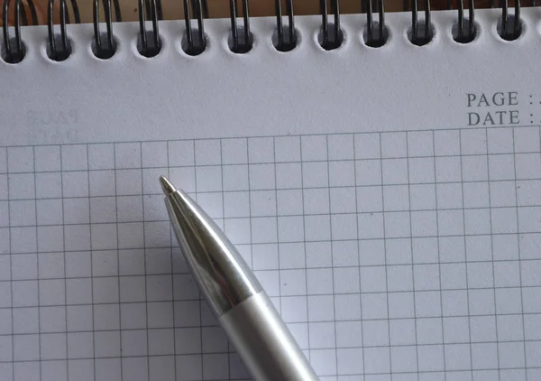 close up of a notebook and a pencil on a white background