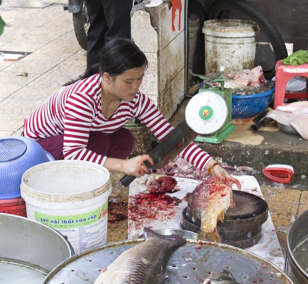 Frau schneidet einen Fisch auf dem Markt — Stockfoto