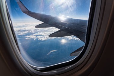 Bulutların üzerinde uçan bir uçağın kanadının pencereden görüntüleme