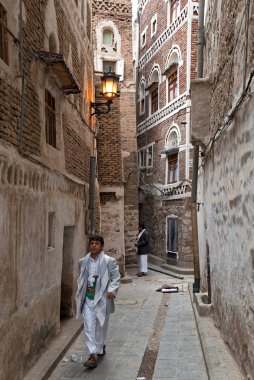 Geleneksel giysiler içinde genç bir adam dar sokaklarda 4 Mayıs 2007 Sanaa, Yemen yürür. Sanaa eski şehir Unesco Dünya Miras kenti olduğunu.