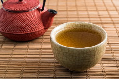 Fincan çay ve Japon geleneksel tarzı kırmızı çaydanlık doğal hasır üzerinde