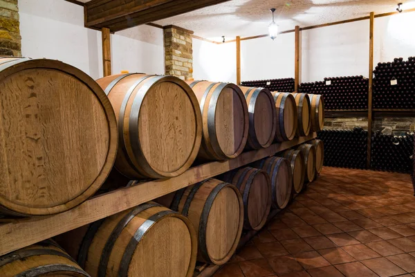 在希腊埃拉斯托纳一家酒厂的酒窖里堆放酒桶和酒瓶 — 图库照片