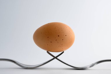 Beyaz arka plan üzerinde iki çatal üzerinde dengede yumurta