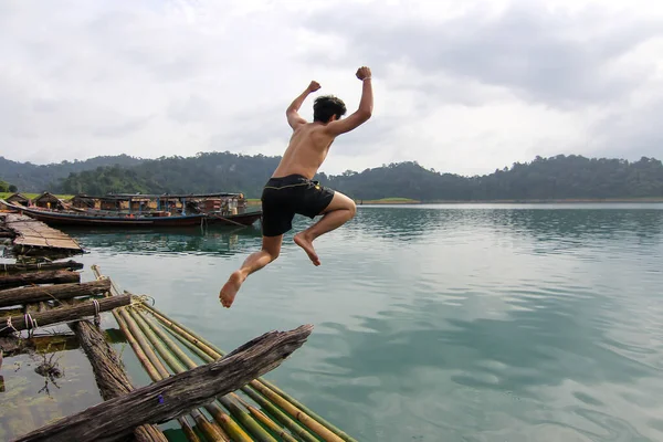 The asia man jump from wood to the river at thailand