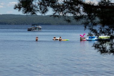 Killaloe, Ontario / Kanada - 24 Temmuz 2020: Tekneler geçerken gölde yüzme cihazıyla oynayan bir grup insan 