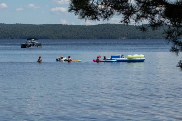 Killaloe, Ontario / Kanada - 24 Temmuz 2020: Tekneler geçerken gölde yüzme cihazıyla oynayan bir grup insan 