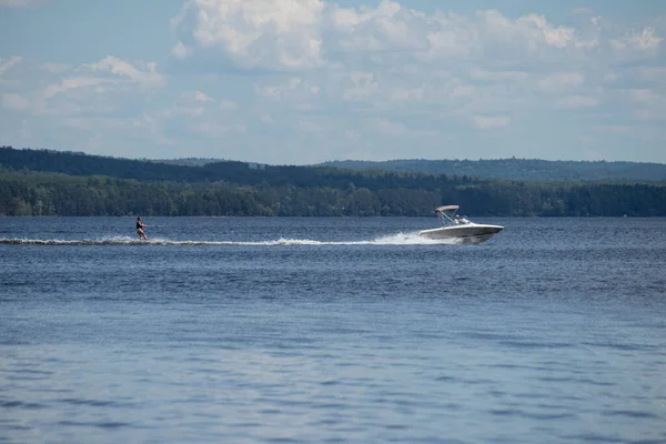 Kanada, Ontario 'daki Round Lake' te büyük bir teknenin arkasında su kayağı yapan kişi. 