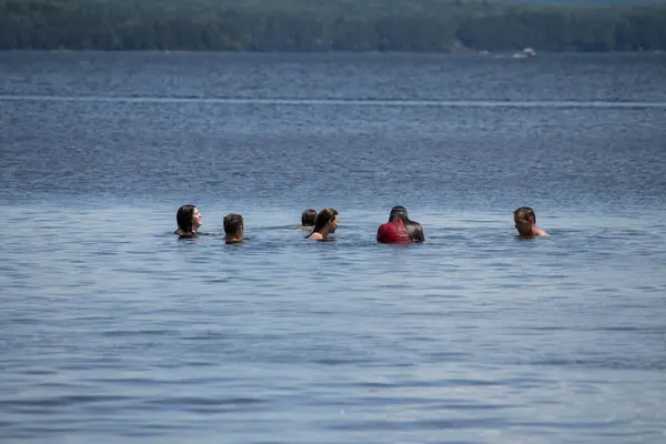 Killaloe, Ontario / Kanada - 24 Temmuz 2020: Göl boynu yüksekliğinde suda oturan bir grup insan.
