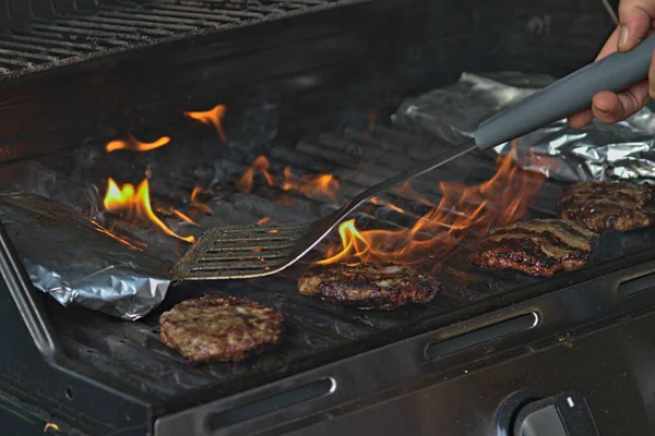 Alüminyum folyoya sarılı hamburgerler ve patatesler barbeküde pişiriliyor. 