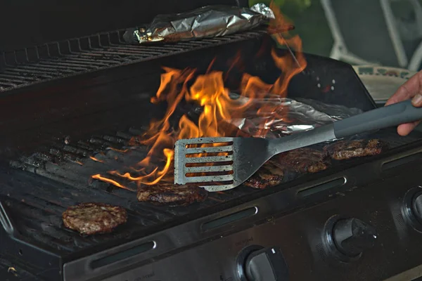 Alüminyum folyoya sarılı hamburgerler ve patatesler barbeküde pişiriliyor. 