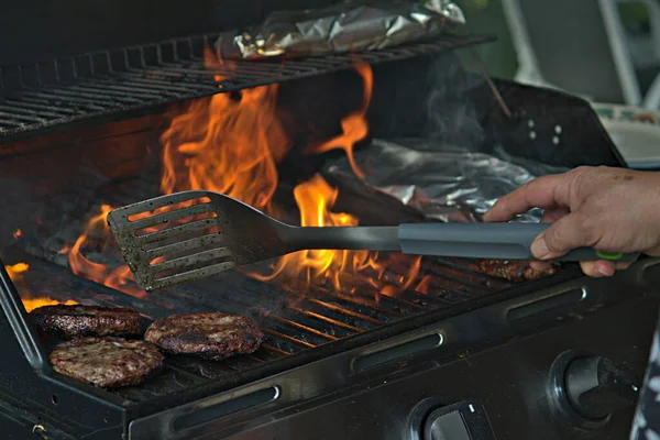 Alüminyum folyoya sarılı hamburgerler ve patatesler barbeküde pişiriliyor. 
