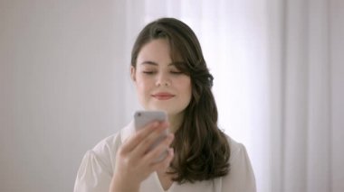 Telefona bakan bir kadın. Kadın parmaklarıyla yukarı doğru kayıyor..