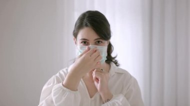 Koronavirüsten korunmak için maskesini takan kadın. Kadın beyaz arka plana karşı ve kameraya bakıyor.