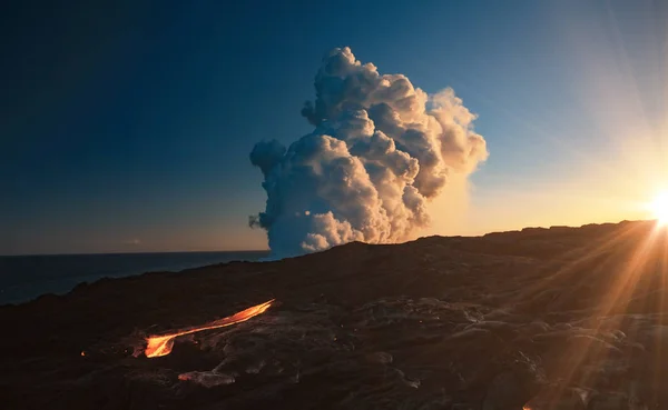 Kilaulea volcano eruption, lava flows into the ocean and steam cloud rising against sunset background