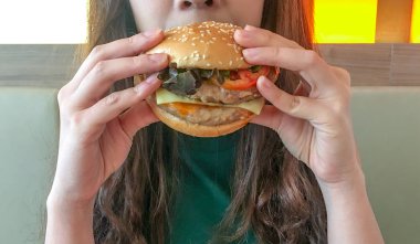 Kadın restoranda taze sebze ile bir hamburger yiyor