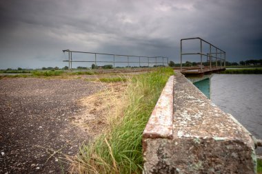 Eski ve harap vintage sur boyunca waterfront bir nehir landaschap Hollanda'nın içinde. Terk edilmiş durumda beton bağlama İskelesi.
