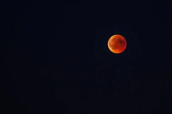 Moon in the starry sky with a blood red color as a result of a lunar eclipse through the earth.