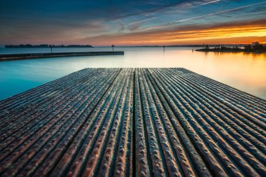 Mimari bakış açısı ile su ve güneşli gün batımında sakin su iskelede